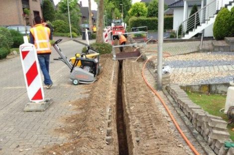 Aufgepflügte gepflasterte Straße zur Verlegung eines Kabels.