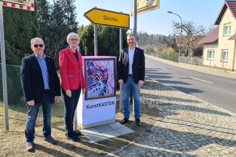 3 Personen zusammen vor einem zum Kunstkasten verhüllten Netzverteiler an einer Straße in Neustadt an der Spree.