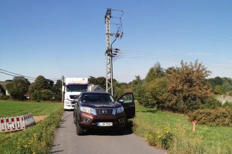 Breitbild: links der Spülbohrer, in der Mitte eine kleine Straße mit weißem LKW und weinrotem PKW. Rechts die Autobahn.