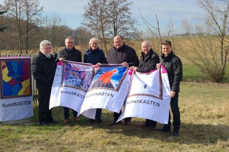 5 Personen zusammen vor einem zum Kunstkasten verhüllten Netzverteiler auf einer Wiese in Crostwitz. Die Personen präsentieren 3 weitere "Kunsthüllen".