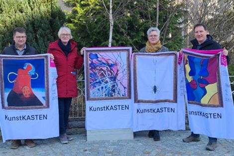 4 Personen zusammen vor einem zum Kunstkasten verhüllten Netzverteiler an einer Straße in Malschwitz. Die Personen präsentieren 3 weitere "Kunsthüllen".