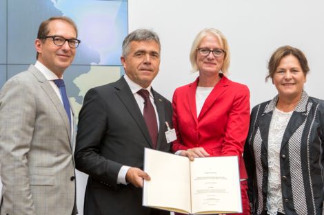 4 Personen halten ein Buch in der Hand.